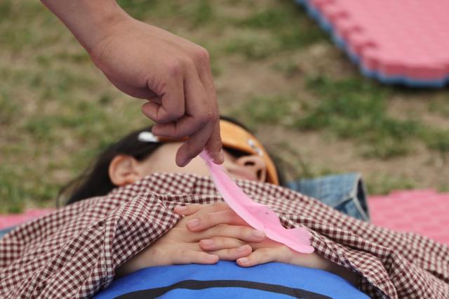 An official tickles a participants hand with a feather at the 2026 Han River Napping Championship held at Mulbit Plaza in Yeouido Hangang Park Yeongdeungpo-gu Seoul May 2 2026 AJP Han Jun-gu