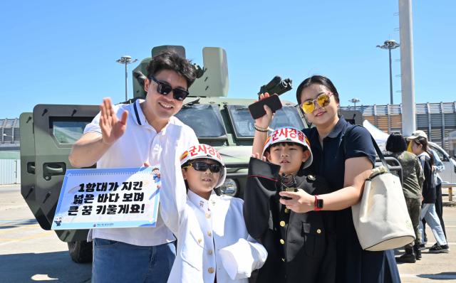 이번 부대개방행사에 참가한 가족이 소형전술차량 앞에서 군사경찰 복장을 체험하고 있다 사진해군1함대