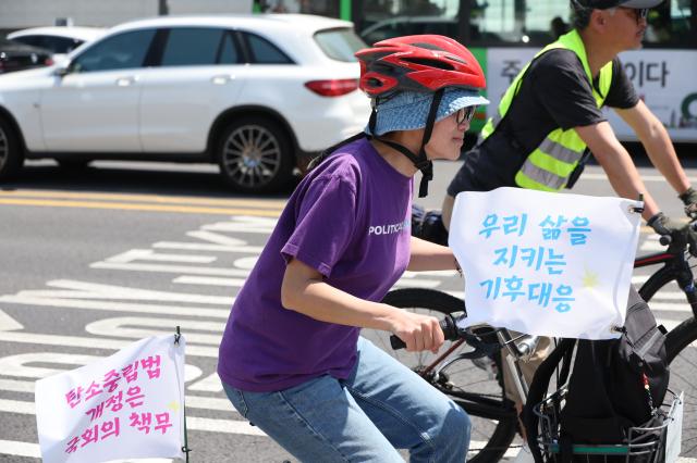 Climate activists ride bicycles through Gwanghwamun Square in Seoul to urge the National Assembly to promptly revise the Carbon Neutrality Act May 13 2026 AJP Han Jun-gu
