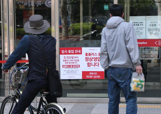 Customers at Homeplus Jamsil store review a notice about the suspension of operations.