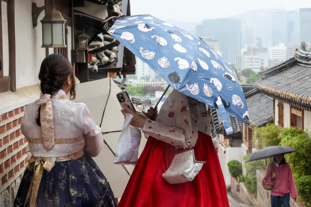 Tourists walk with umbrellas at Bukchon Hanok Village in Seoul’s Jongno District on May 20 as rain falls across the country AJP Yoo Na-hyun