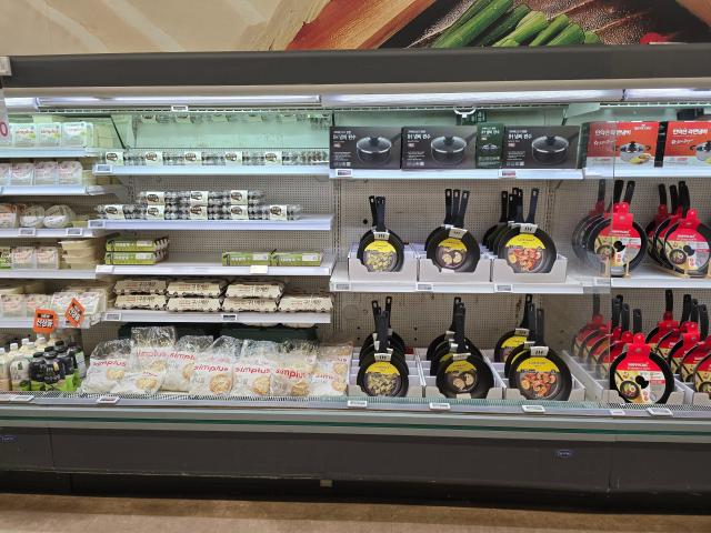 Egg and tofu shelves stacked with frying pans at Homeplus 