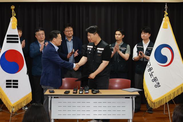 Yeo Myung-gu head of the People Team for Samsung Electronics’ Device Solutions DS division and Choi Seung-ho chief of the Samsung Electronics branch of the Samsung Group Super Enterprise Labor Union shake hands after signing a provisional wage agreement following labor talks at the Gyeonggi Regional Labor Office in Suwon Gyeonggi Province on May 20 2026 JOINT PRESS CORPS