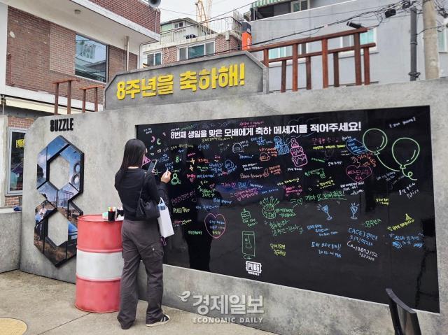 펍지 성수에 위치한 메시지 월에 방문객이 8주년을 맞이한 배틀그라운드 모바일에 메시지를 남기고 있다 사진류청빛 기자