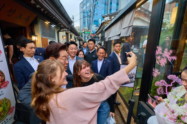 President Lee Jae-myung takes a photo with foreign tourists during his visit to Ikseon-dong Hanok Street in Seoul on May 21.