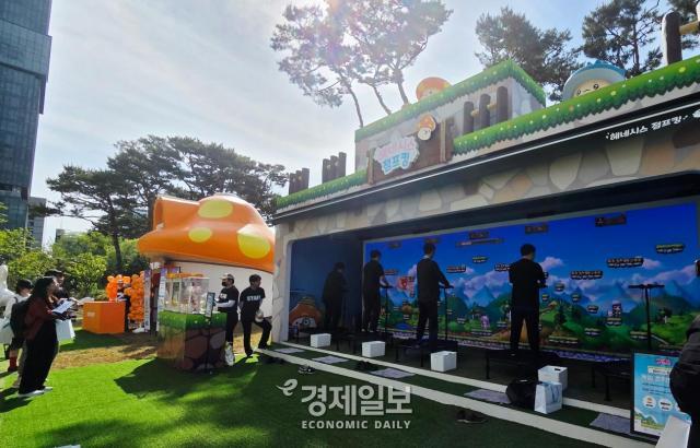 주황 버섯 모양의 경품 교환처 옆에 위치한 현장 체험형 콘텐츠 헤네시스 점프킹에서 이용자들이 점프맵 미니게임을 하고 있다 사진류청빛 기자