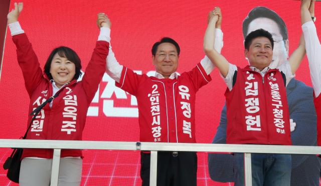 유정복 인천시장 후보가 25일 중구 영종도 운서역 유세 현장에서 김정헌 임옥주 후보와 손을 맞잡고 시민들에게 인사하고 있다 사진유정복 후보
