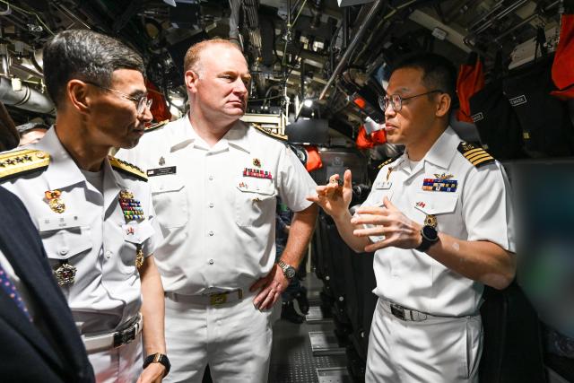 Republic of Korea Navy Chief of Naval Operations Adm Kim Kyung-ryul left and Rear Adm David Patchell center commander of Canada’s Pacific Fleet listen to Capt Lee Byung-il commanding officer of the ROKS Dosan Ahn Chang-ho aboard the submarine at the Esquimalt naval base in Victoria Canada on May 25 2026 Courtesy of the ROK Navy
