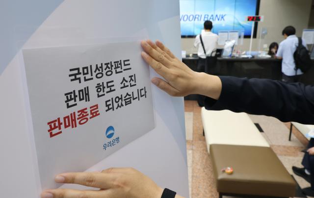 국민참여성장펀드 가입 첫날인 22일 서울 중구 우리은행 본점 영업점에서 한 직원이 한도소진으로 인한 판매종료 안내문을 붙이고 있다 사진연합뉴스