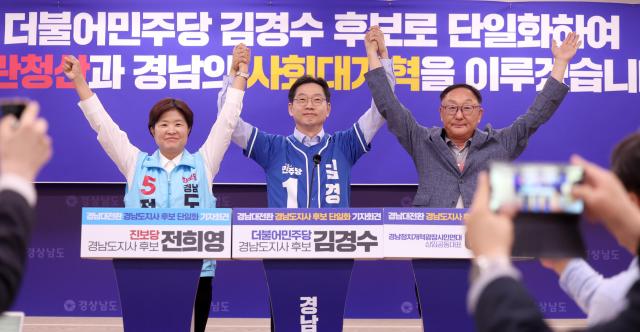 더불어민주당 김경수 경남지사 후보와 진보당 전희영 후보가 27일 경남도청 프레스센터에서 열린 경남대전환 경남도지사 후보 단일화 긴급 기자회견에서 손을 들어 인사하고 있다 왼쪽부터 전 후보 김 후보 이병하 경남정치개혁광장시민연대 상임공동대표 사진연합뉴스