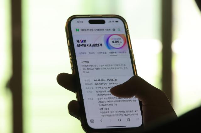 A citizen searches for early voting locations for the 9th National Simultaneous Local Elections on a smartphone in Banpo Seoul on May 29 2026 Photo AJP Han Jun-gu