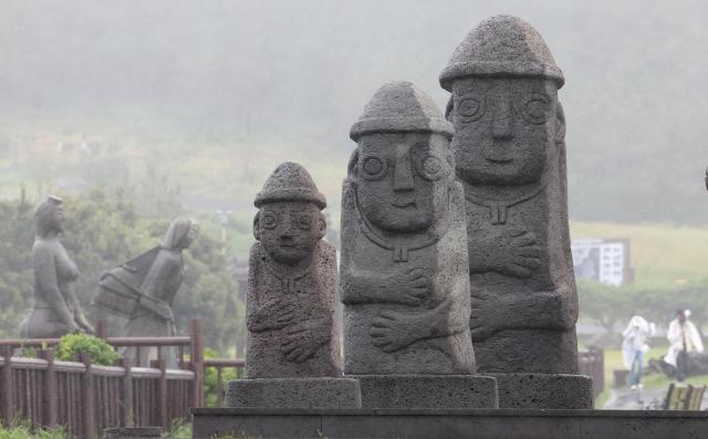 A tourist wearing a raincoat walks at Songaksan in Daejeong-eup Seogwipo Jeju Island amid strong winds and rain on May 26 2026 Yonhap 