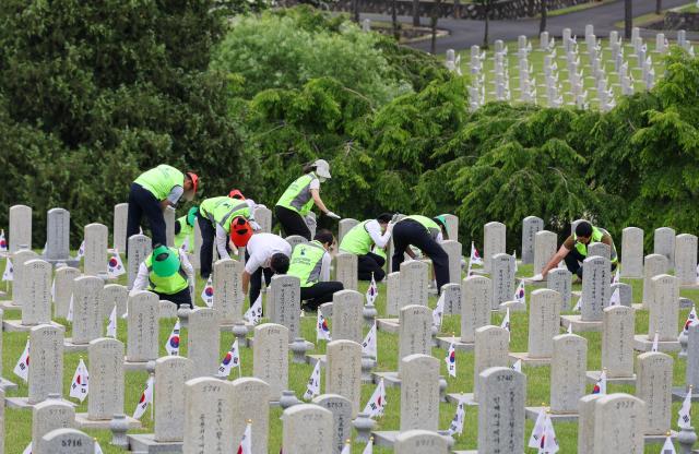 Members of a volunteer group from the Seoul Central District Court clean headstones at the Seoul National Cemetery in Seoul on June 1 2026 during the Month of Patriots and Veterans AJP Yoo Na-hyun