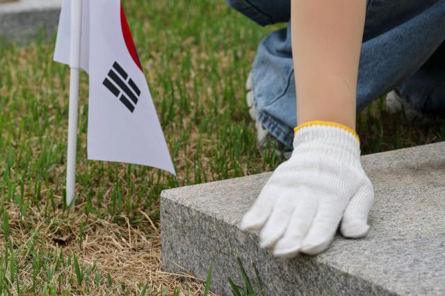 Members of a volunteer group from the Seoul Central District Court clean headstones at the Seoul National Cemetery in Seoul on June 1 2026 during the Month of Patriots and Veterans AJP Yoo Na-hyun