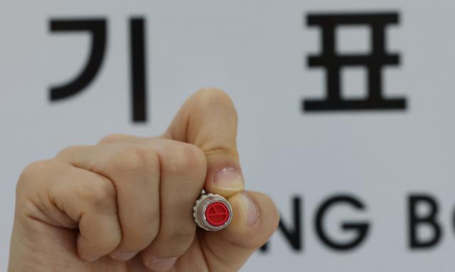 An election official displays a ballot stamp at Seongbuk-dong No 1 Polling Station set up at the Seongbuk-dong Community Service Center in Seongbuk-gu Seoul on June 2 2026 Yonhap