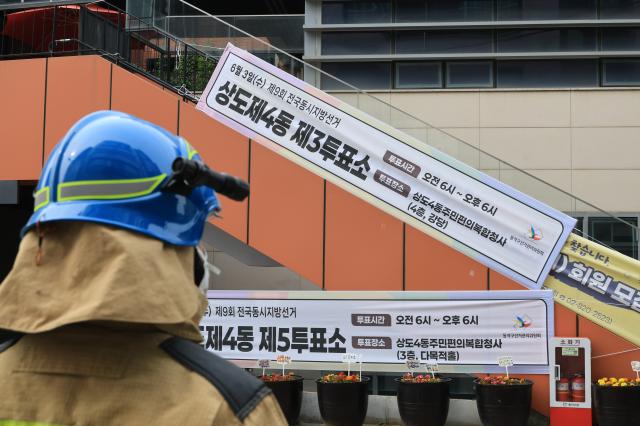 A firefighter looks at a polling station sign outside the Sangdo 4-dong Community Complex in Sangdo-dong Seoul on June 3 2026