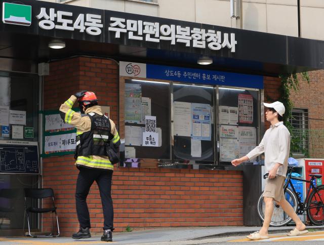 A firefighter and a citizen enter the Sangdo 4-dong Community Complex in Sangdo-dong Seoul following a fire at the building on June 3 2026 AJP Han Jun-gu