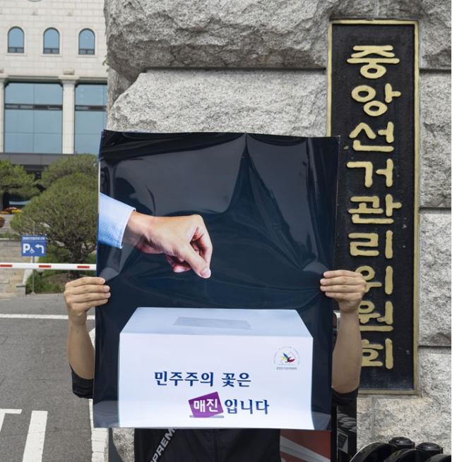 Lee Jae-seok holds up the 'The Flower of Democracy is Sold Out' poster