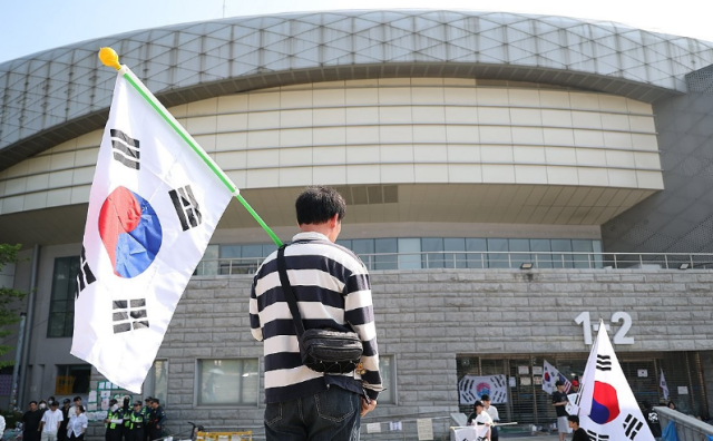 A participant holds a South Korean flag during a protest blockade at the Jamsil counting center on June 11, following the ballot shortage incident during the June 3 local elections.