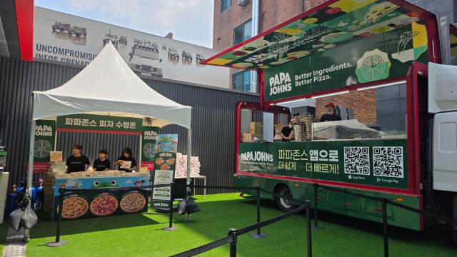 Exterior view of the Papa John's Pizza Planet pop-up store in Seongsu-dong, Seoul, featuring a pizza truck.