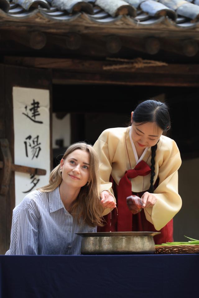A foreign visitor takes part in a calamus water hair-washing experience during a Dano seasonal event in front of Ochon-daek at the National Folk Museum of Korea in Jongno-gu Seoul on June 17 2026 AJP Han Jun-gu