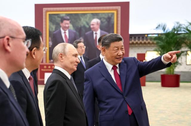 In this pool photograph distributed by the Russian state agency Sputnik Russias President Vladimir Putin and Chinas President Xi Jinping tour a photo exhibition on Russia-China ties in Beijing on May 20 2026 Reuters-Yonhap 