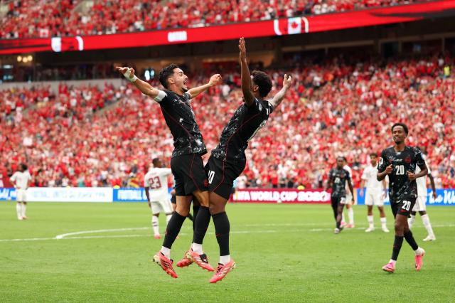 Canadas Jonathan David left celebrates with a teammate after scoring during a Group B match against Qatar at BC Place Vancouver in Vancouver Canada on June 18 2026 AFPYonhap