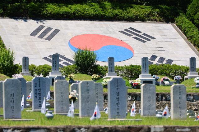 A large Taegukgi emblem is inlaid into the hillside behind grave markers at Seoul National Cemetery in Dongjakdong Dongjak-gu Seoul on June 23 2026 AJP Han Jun-gu