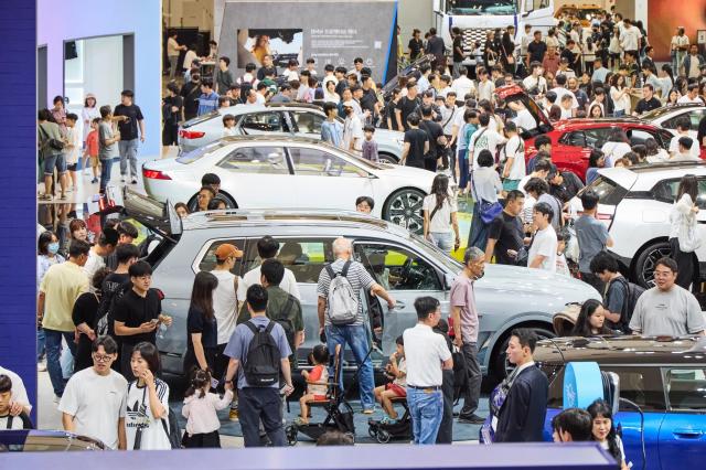 Visitors at the 2024 Busan Mobility Show examining vehicles.