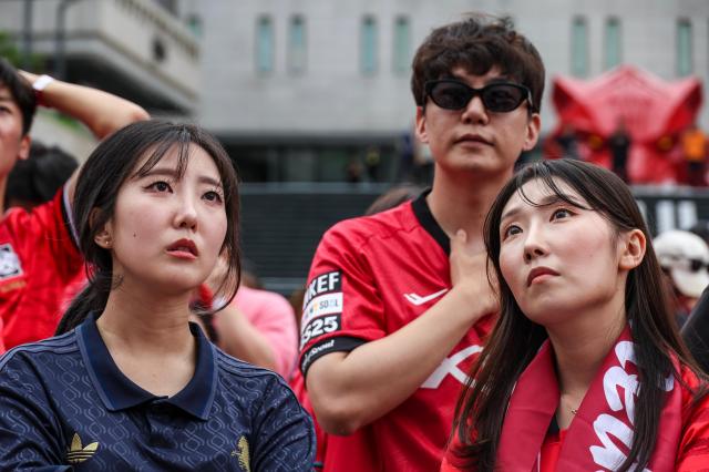 Supporters, including members of the Red Devils, South Korea's official football supporters' group, react with disappointment as they watch the second half of the Group A match between South Korea and South Africa during a public viewing event for the 2026 FIFA World Cup at Gwanghwamun Square in Seoul on June 25, 2026. AJP Yoo Na-hyun.

