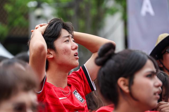Supporters, including members of the Red Devils, South Korea's official football supporters' group, react with disappointment as they watch the second half of the Group A match between South Korea and South Africa during a public viewing event for the 2026 FIFA World Cup at Gwanghwamun Square in Seoul on June 25, 2026. AJP Yoo Na-hyun.

