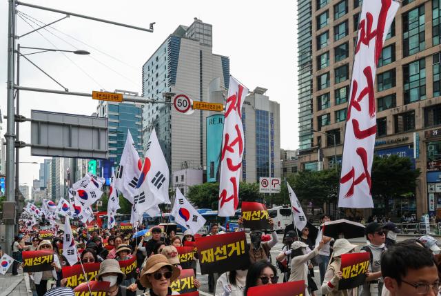 Participants march through the Hongdae area during a rally calling for a presidential election rerun organized by the conservative youth group BOSS Hongdae in Seoul on June 27, 2026. AJP Yoo Na-hyun

