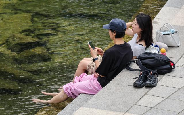 Residents cool off by the Cheonggyecheon Stream in central Seoul on June 30 as a heat advisory remains in effect across the capital AJP Yoo Na-hyun


