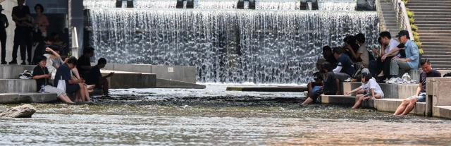 Residents cool off by the Cheonggyecheon Stream in central Seoul on June 30 as a heat advisory remains in effect across the capital AJP Yoo Na-hyun
