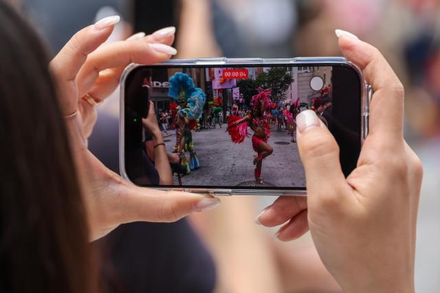 A tourist records a special samba street performance by Lotte World Adventure performers on UNESCO Street in Seouls Myeong-dong district on July 1 2026 AJP Yoo Na-hyun


