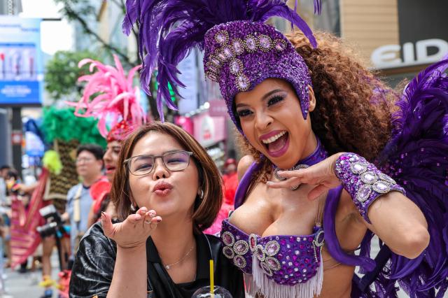Lotte World Adventures samba performers pose for photos with tourists after a special street performance on UNESCO Street in Seouls Myeong-dong district on July 1 2026 AJP Yoo Na-hyun