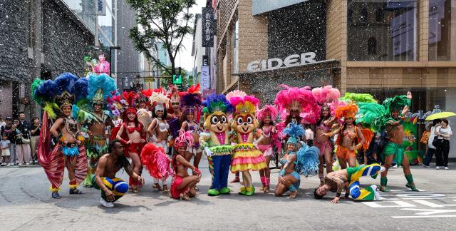 Lotte World Adventures samba performers pose for photos with tourists after a special street performance on UNESCO Street in Seouls Myeong-dong district on July 1 2026 AJP Yoo Na-hyun
