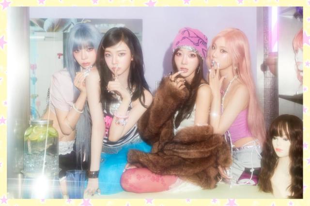 A teaser image for aespas debut Japanese EP KISS N TELL The members pose in front of a mirror amid salon props including wigs and mannequin heads continuing the playful girlish concept of the release Courtesy of SM Entertainment