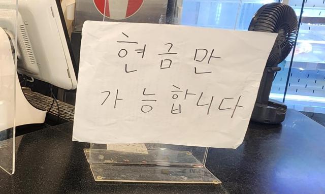 A notice stating 'Cash only' is posted at a rental store in Homeplus World Cup store in Seongsan-dong, Seoul