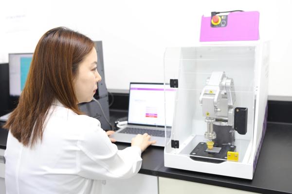 코스맥스 RIResearchInnovation 유닛 연구원이 로봇팔 장비를 활용한 ISO 23675 평가법으로 선케어 제품의 자외선 차단 지수를 측정하고 있는 모습 사진코스맥스