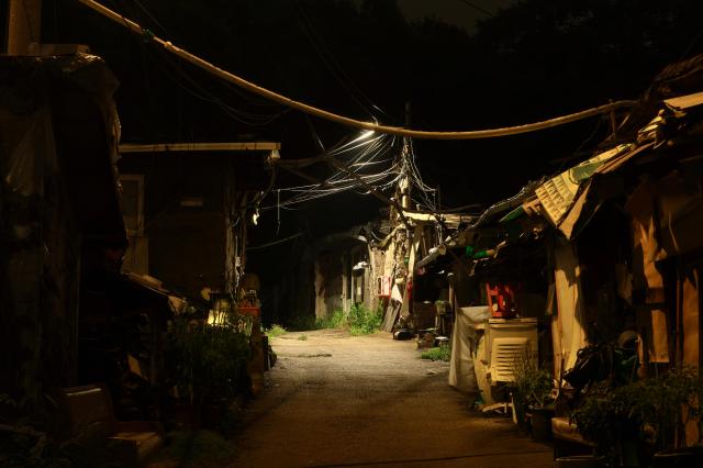 Tangled overhead wires stretch above a dimly lit alley in Guryong Village Seoul South Korea at night AJP Han Jun-gu