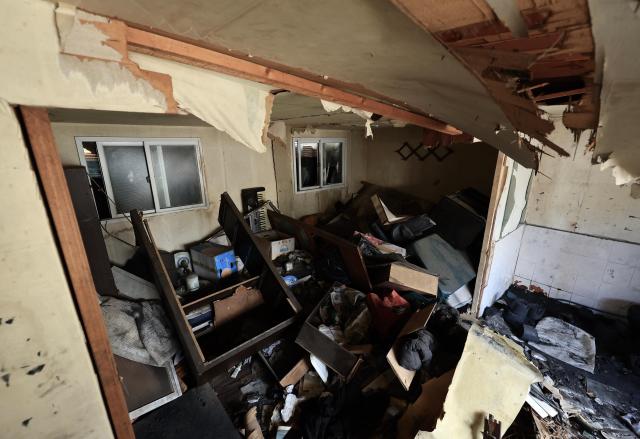 The interior of a home shows collapsed ceiling insulation and scattered belongings including a keyboard and boxes in Guryong Village Seoul South Korea AJP Han Jun-gu