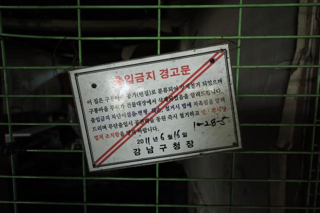 A 2011 notice from the Gangnam District office posted on a green wire fence declares a home an unauthorized structure slated for demolition in Guryong Village Seoul South Korea AJP Han Jun-gu