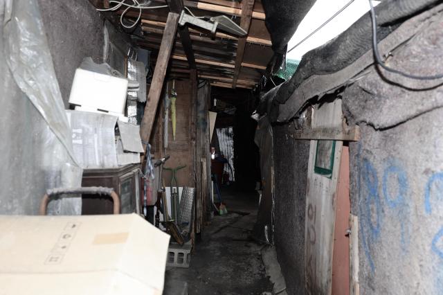  A narrow cluttered passageway inside a Guryong Village dwelling packed with discarded household items an umbrella insulation panels and cardboard in Seoul South Korea AJP Han Jun-gu