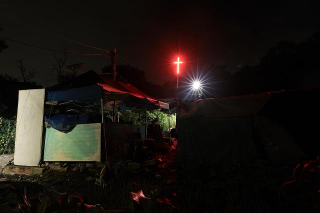  An illuminated church cross rises above the rooftops of Guryong Village Seoul South Korea at night AJP Han Jun-gu