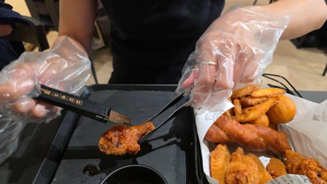 기자가 치킨에 붓으로 양념을 바르는 소스 도포 작업을 체험하고 있다. [사진=김현아 기자]