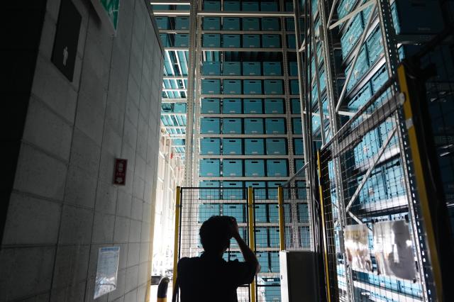 Interior view of the automated storage system at the Coupang facility showing tall racks stacked with blue storage bins reaching toward the ceiling 20260720 AJP Han Jun-gu