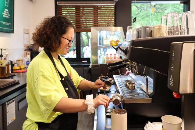 Choi Yu-mi prepares a cup of coffee at the Oreum Café July 22 2026 AJP Yoo Na-hyun