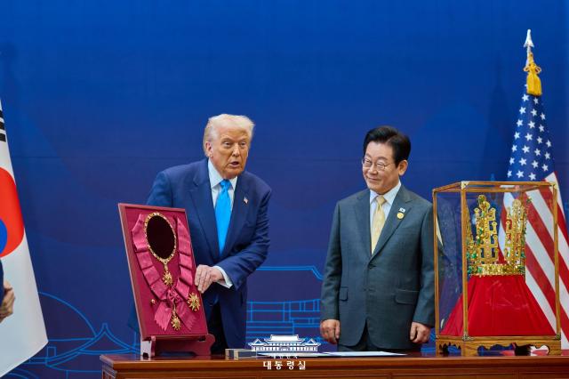 US President Donald Trump left and South Korean President Lee Jae Myung stand beside the Grand Order of Mugunghwa and a replica of the Silla-era Cheonmachong gold crown during a ceremony at the Gyeongju National Museum in Gyeongju South Korea on Oct 29 2025 Lee presented Trump with South Korea’s highest state decoration and the crown replica ahead of their summit talks Courtesy of Cheong Wa Dae 