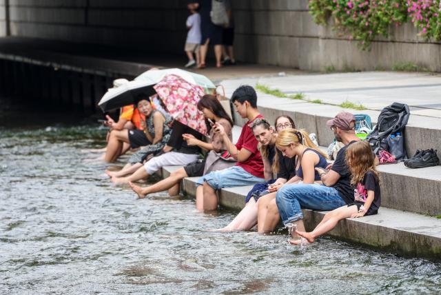 Foreign tourists cool off at Cheonggye Stream in Seoul on July 28 2026 as the daytime high reached 32 degrees Celsius AJP Yoo Na-hyun 